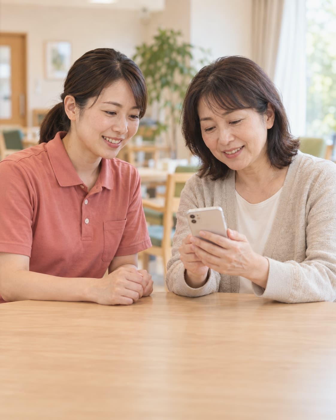 スマートフォンを見ながら穏やかに話す介護スタッフとご家族のイメージ